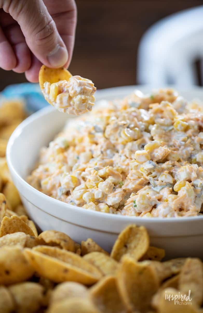 Hand holding a chip with some corn dip.