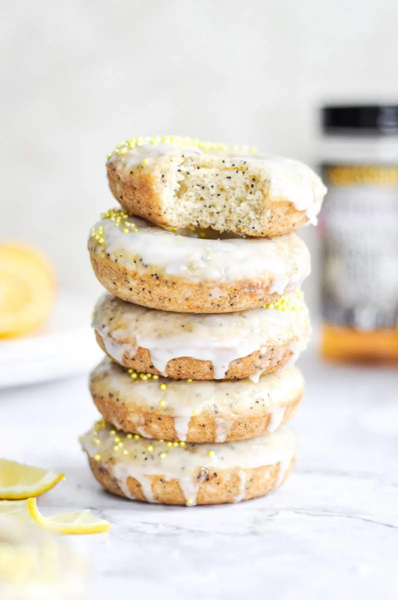 Stack of lemon poppy seed donuts with lemon wedge and slice in the background.