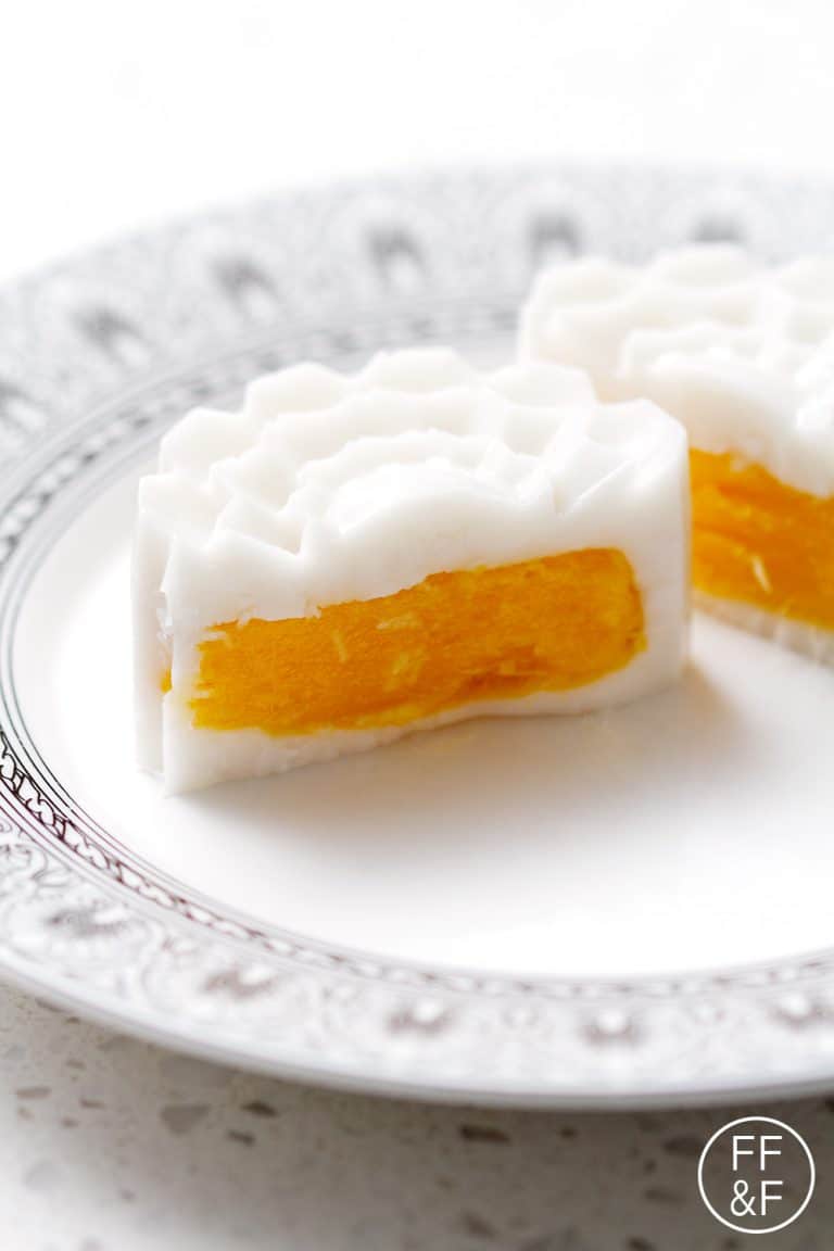 Cut open mango coconut mango mooncakes on a decorative plates.