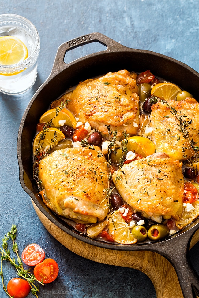 Mediterranean chicken thighs with olives, lemon wedges, and herbs.