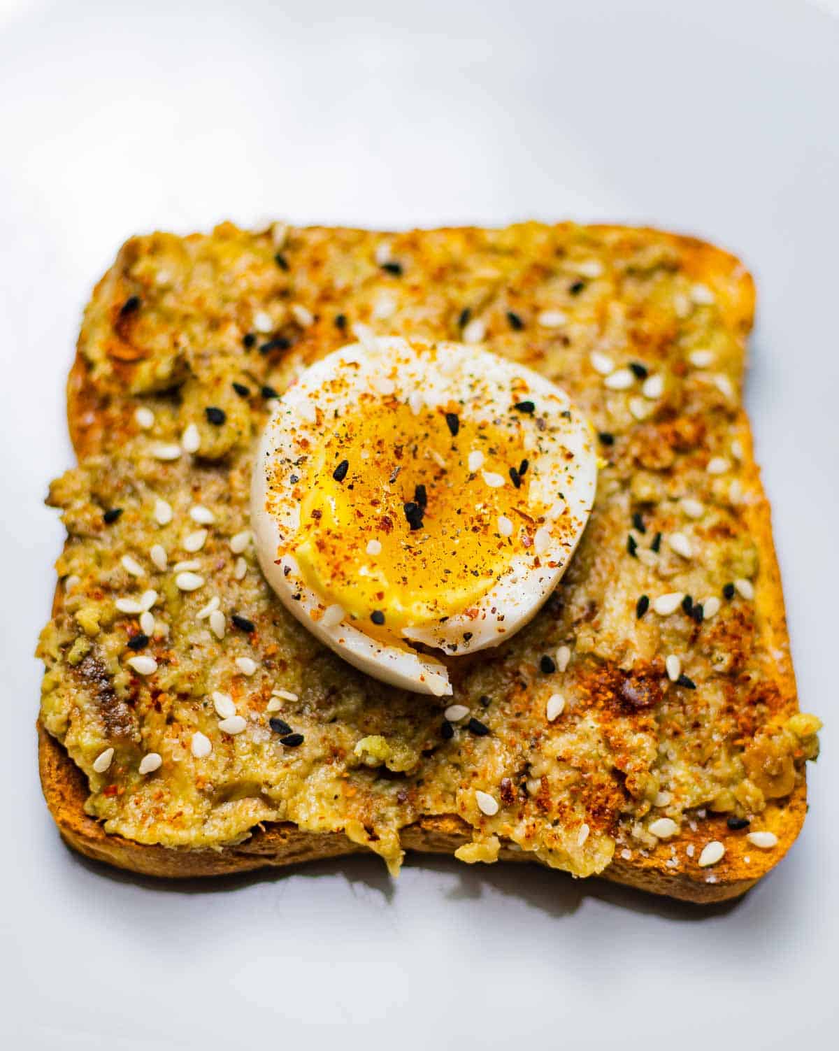 Avocado toast with egg, sesame seeds, and chili pepper.