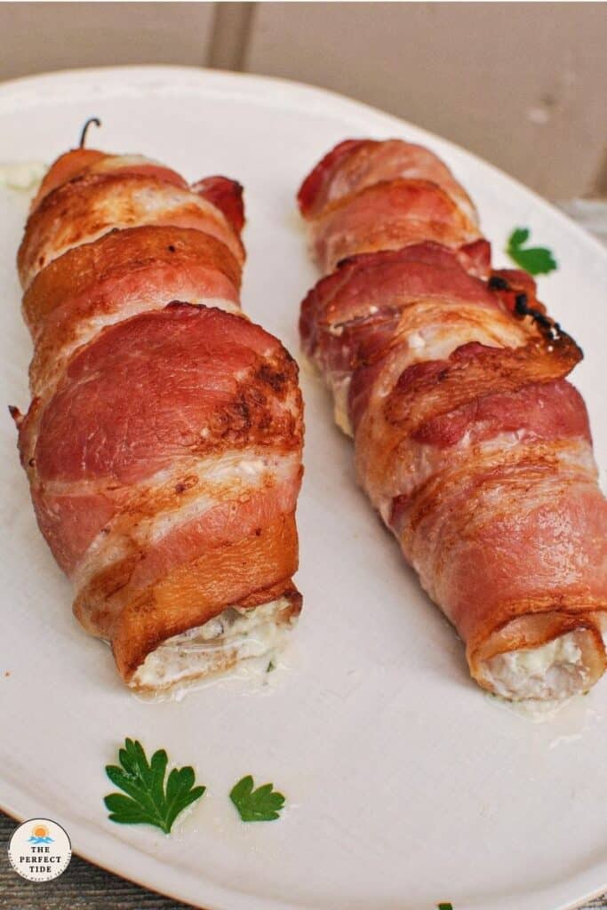 Bacon wrapped fish on a white plate.