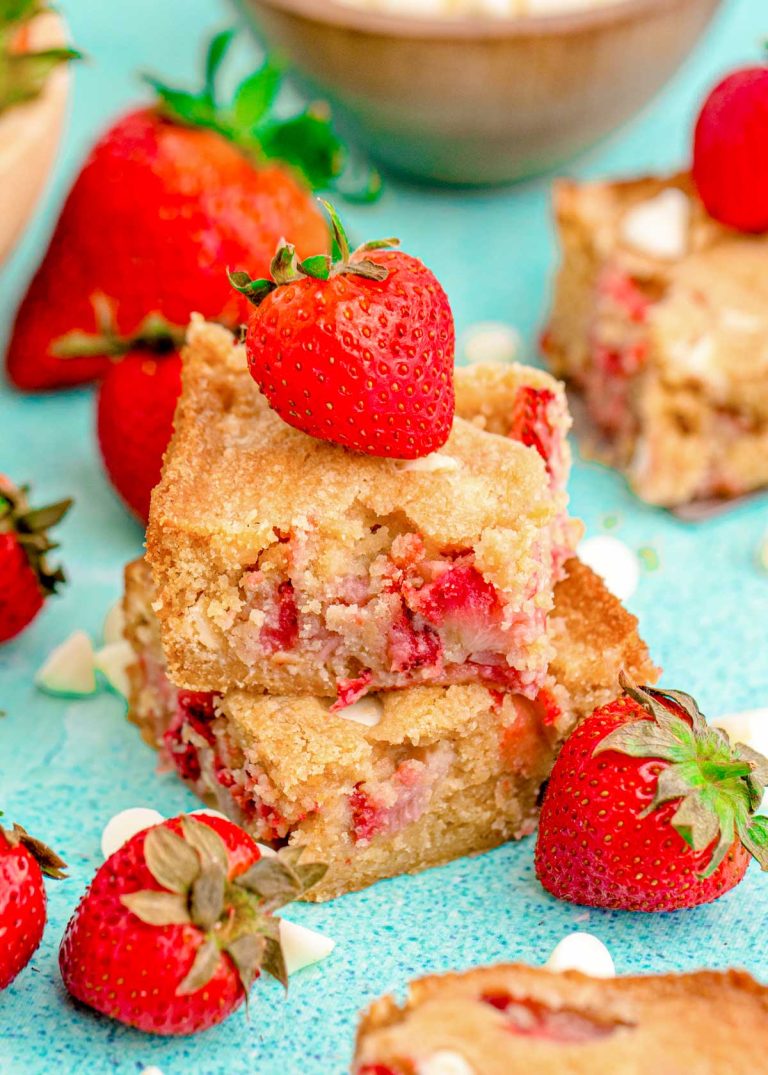 Stack of strawberry blondies with fresh strawberries on top.