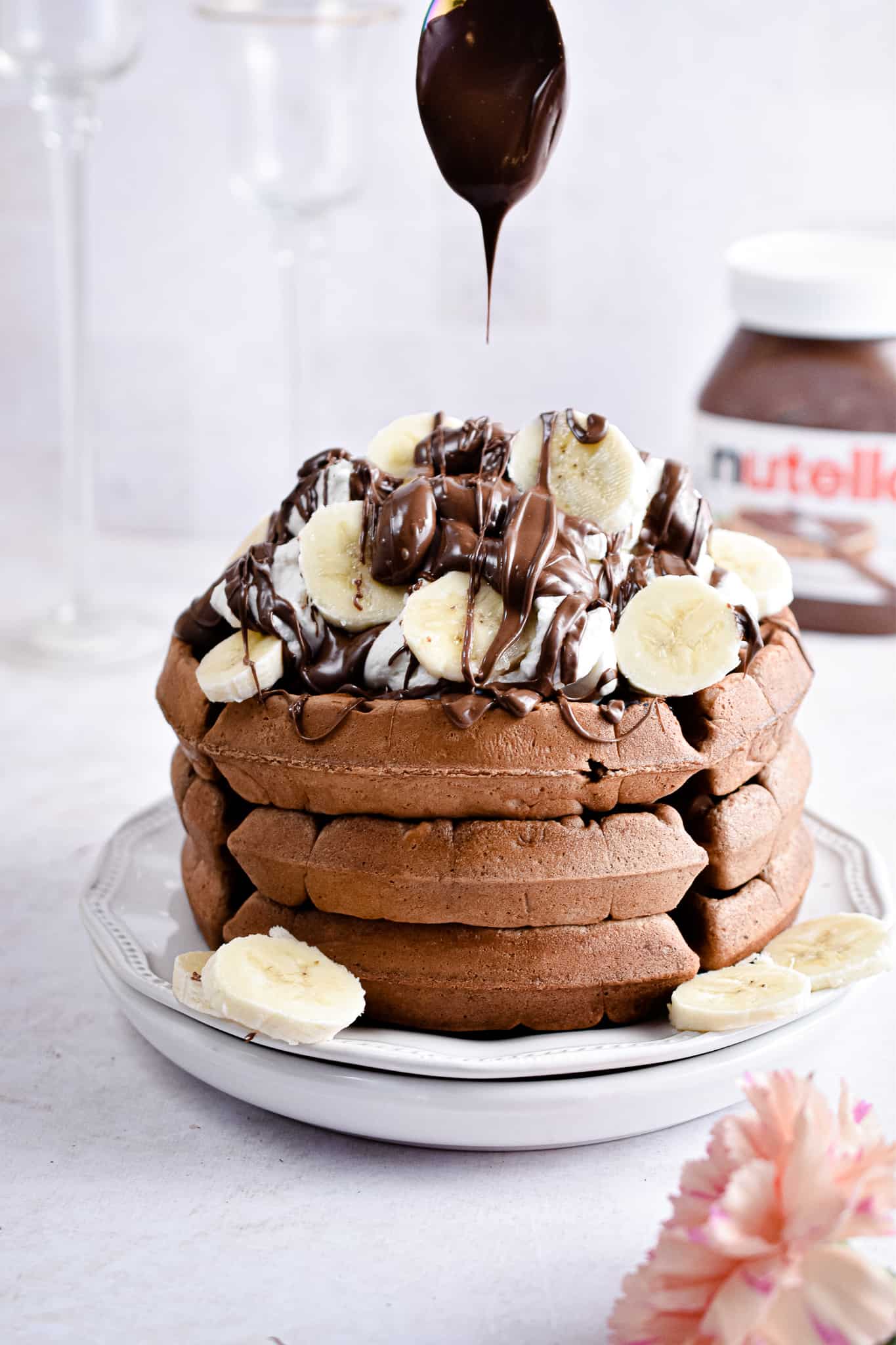 Chocolate waffles topped with sliced bananas and chocolate sauce.