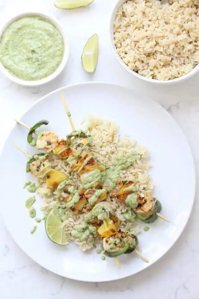 Pineapple jalapeno shrimp skewers with white rice and green sauce.