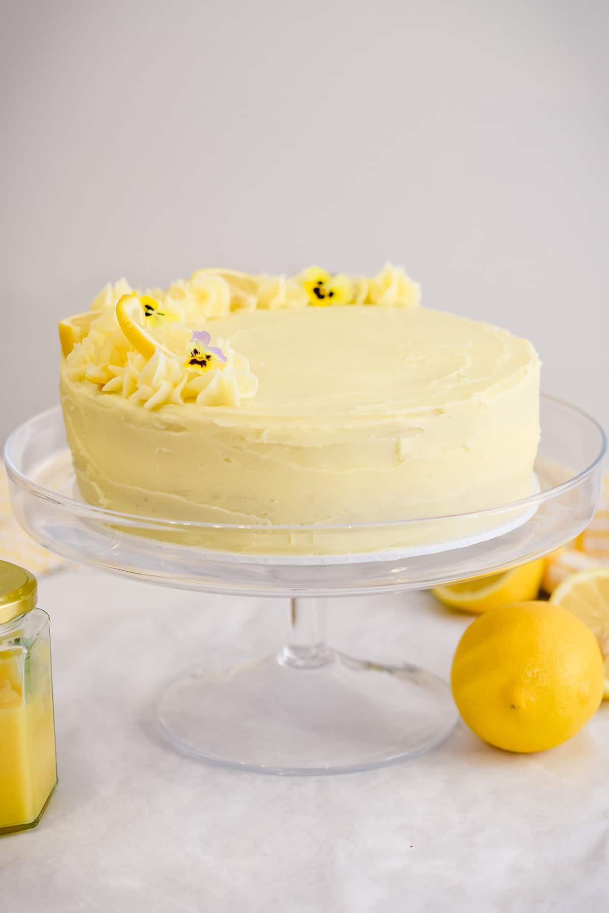 Lemon curd cake with lemon buttercream on a clear cake stand.