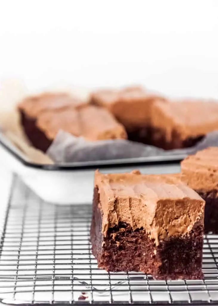 Chocolate brownies with chocolate frosting on a cooling rack.