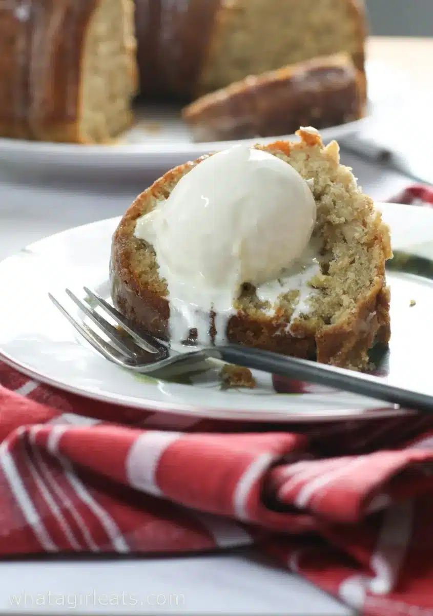 Apple cake with apple cider glaze with a scoop of vanilla ice cream on a plate.