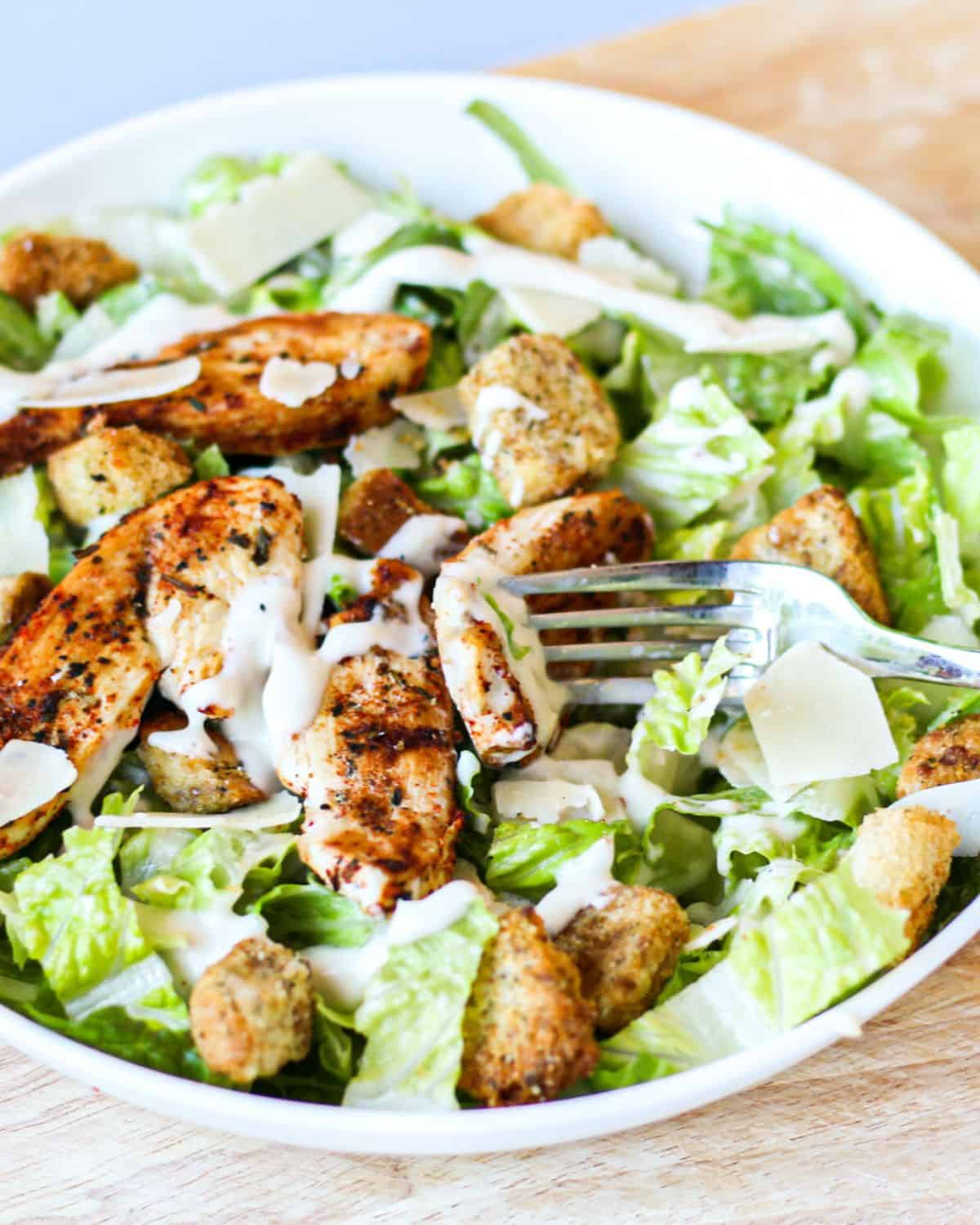 Caesar salad with blackened chicken and fork.