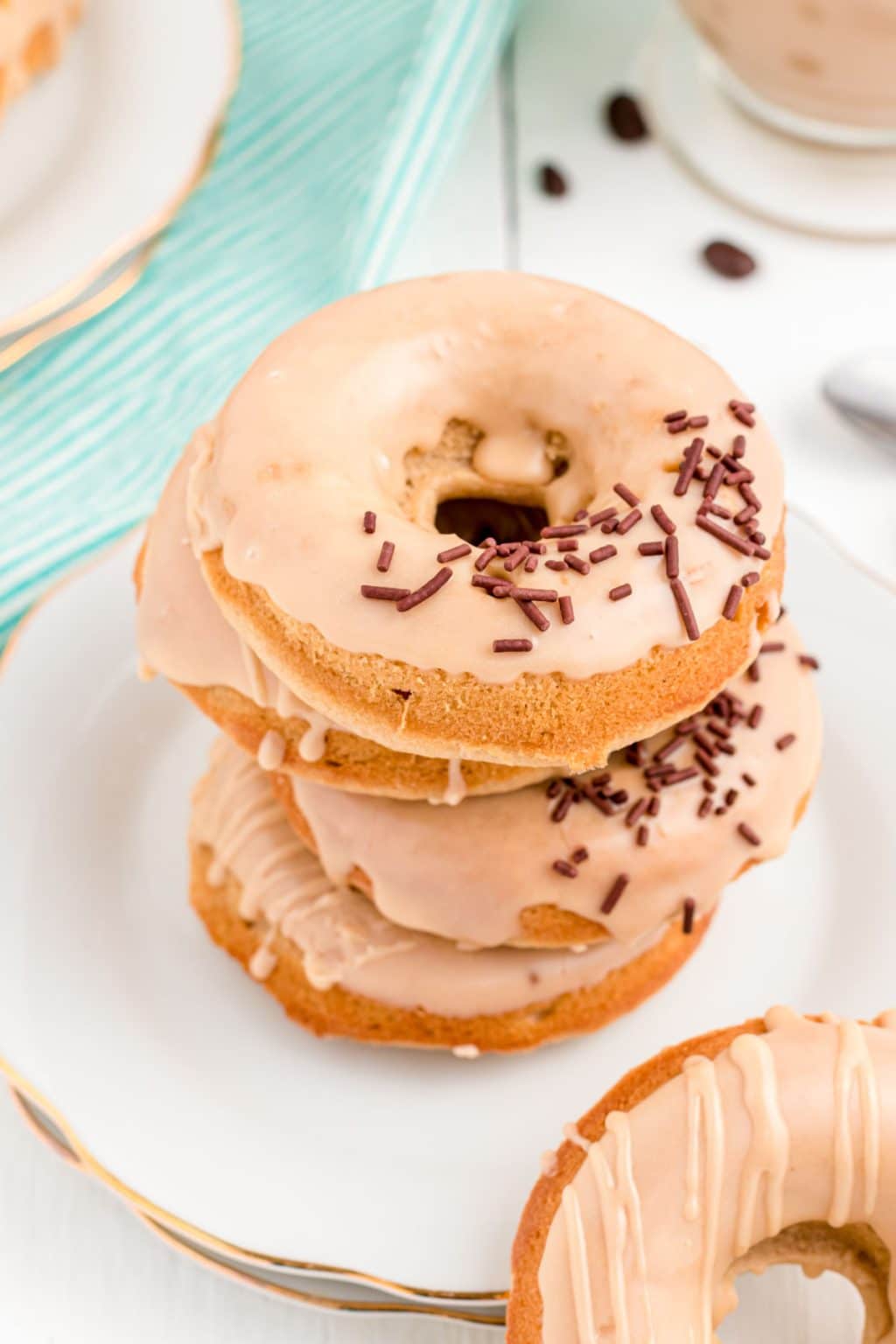 Stack of coffee donuts on a decorative gold rimmed plate.