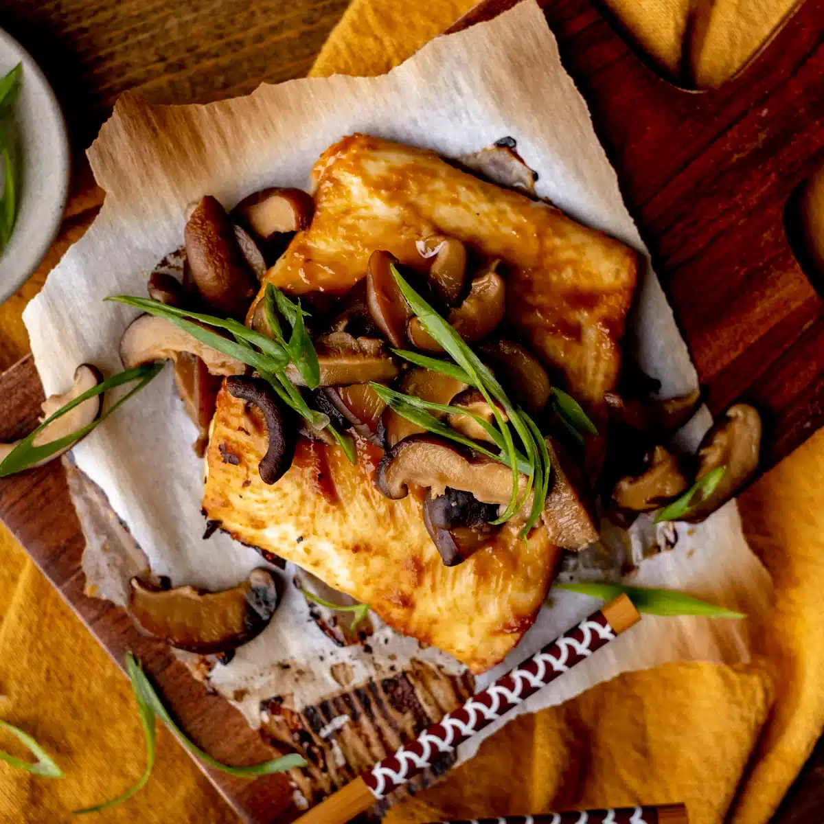 Broiled miso halibut with mushrooms and green onion slices.