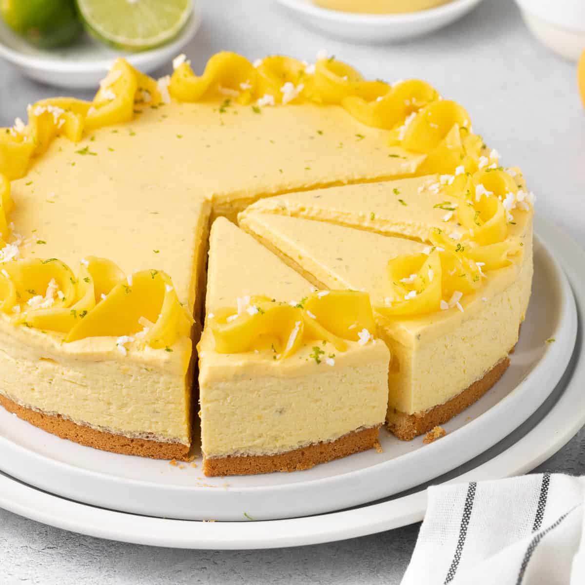 Whole mango mousse cake on a white stand.