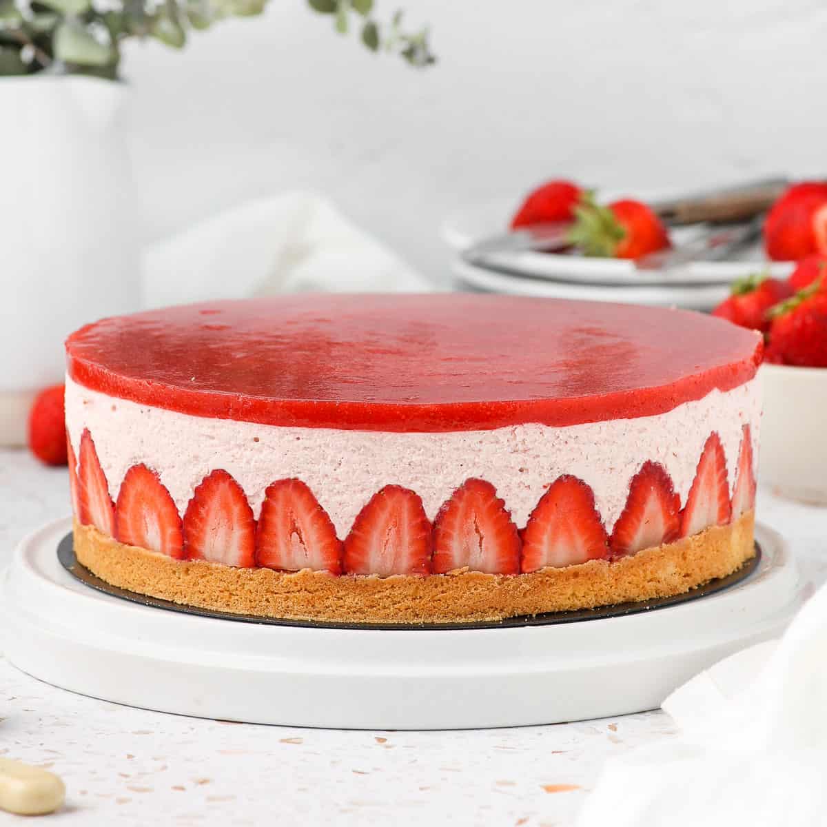 Whole strawberry mousse cake on a white cake platter.