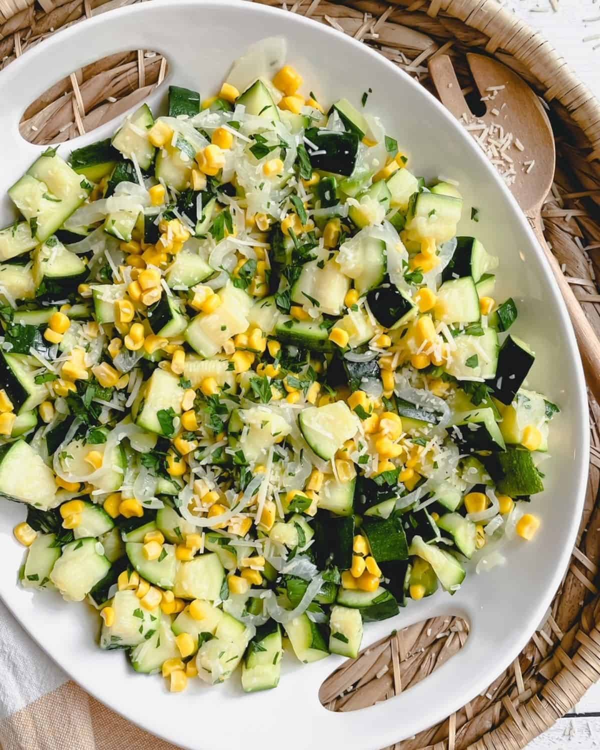 Sauteed zucchini and onions with sweet corn on a white platter.