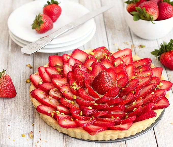 Strawberry tart with pastry cream with ingredients in the background.