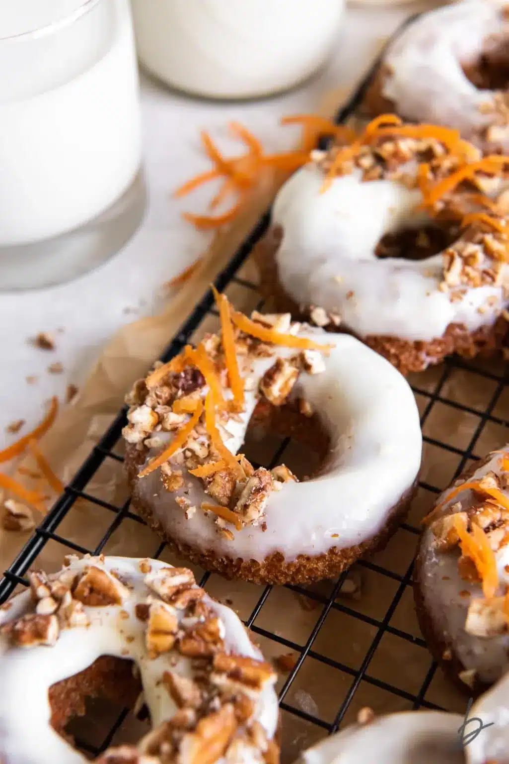 Baked carrot cake donuts on a black cooling rack.