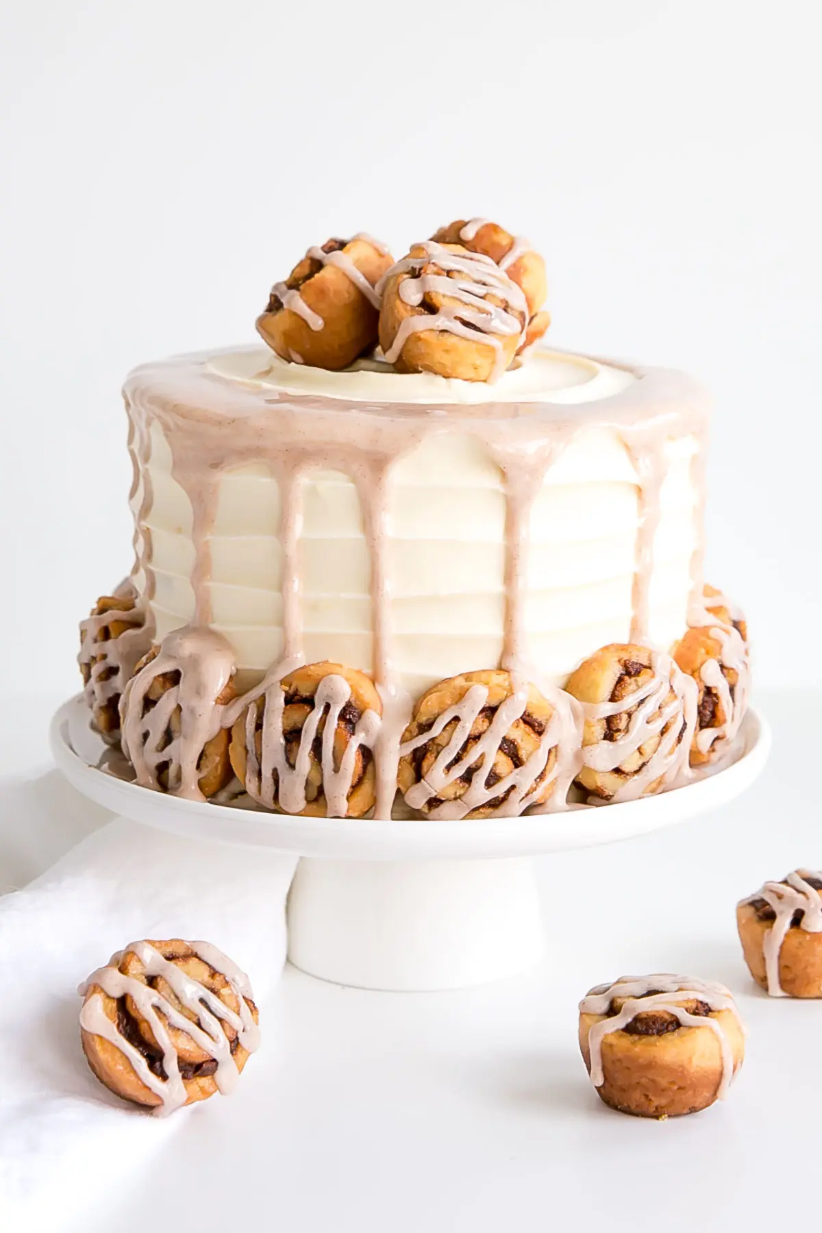 Cinnamon roll cake on a white cake stand.