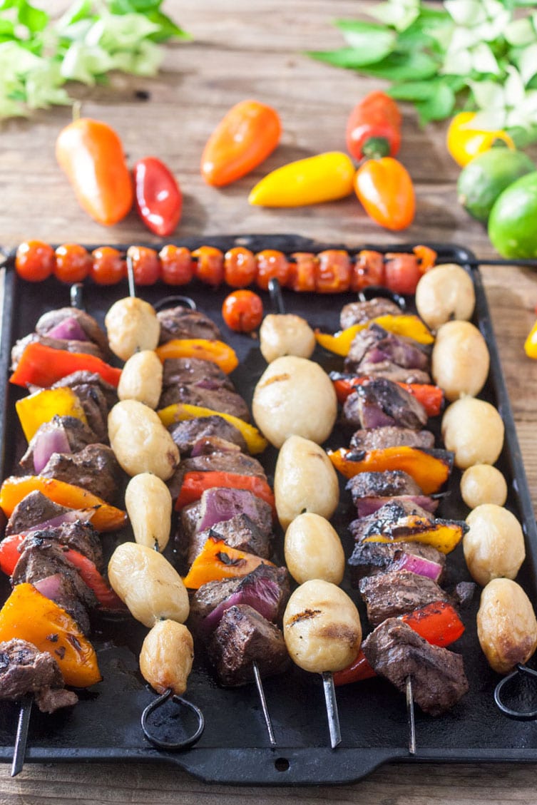 Venison steak kabobs on a black pan.