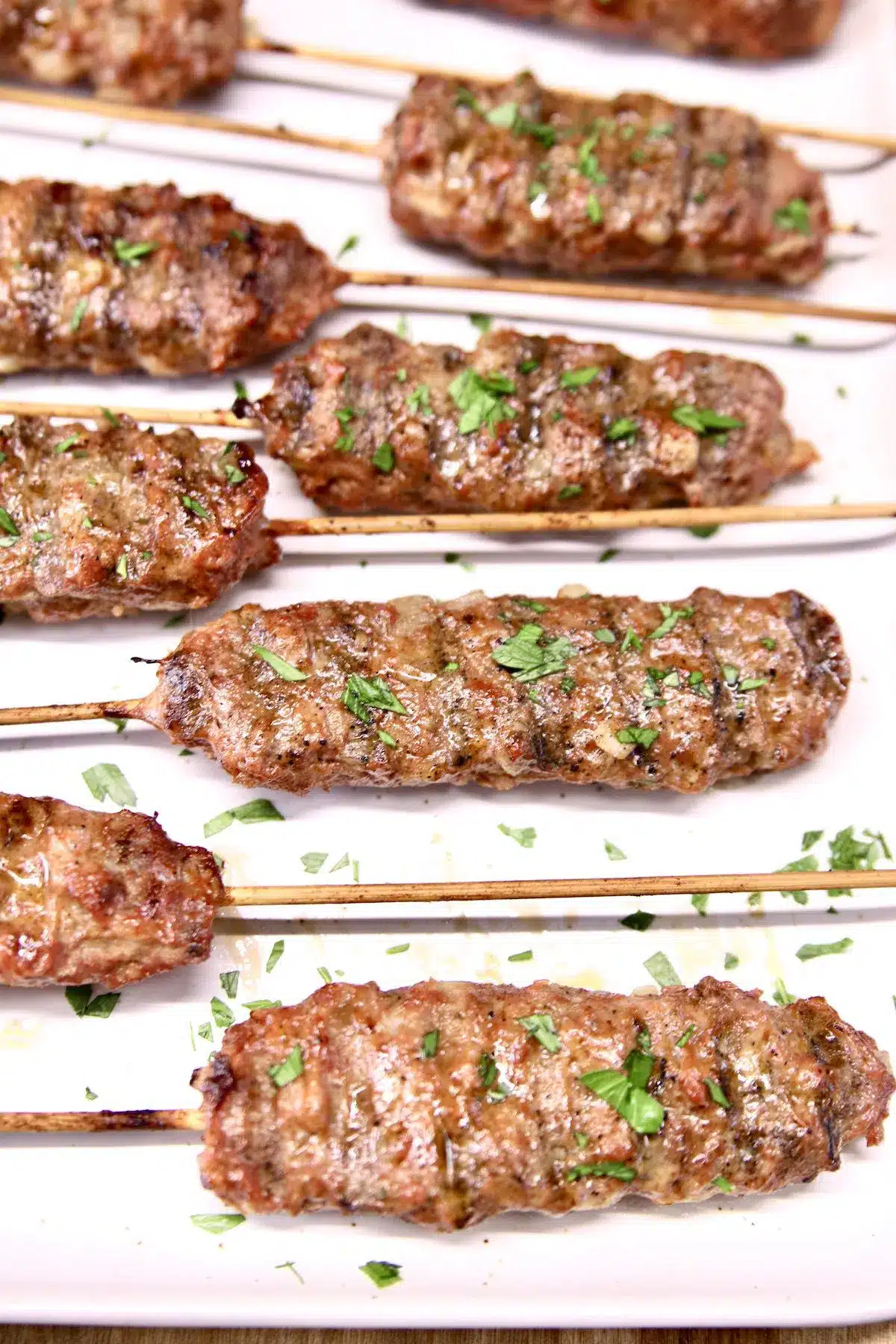 Ground beef kababs on a white platter.