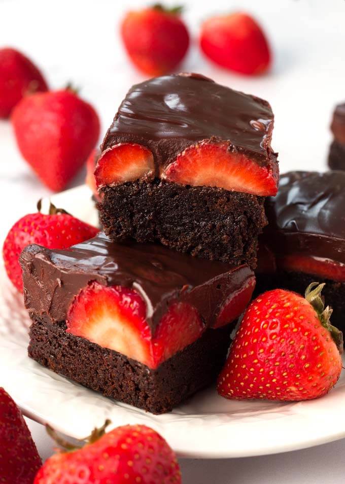 Stack of chocolate covered strawberry brownies on a white plate.