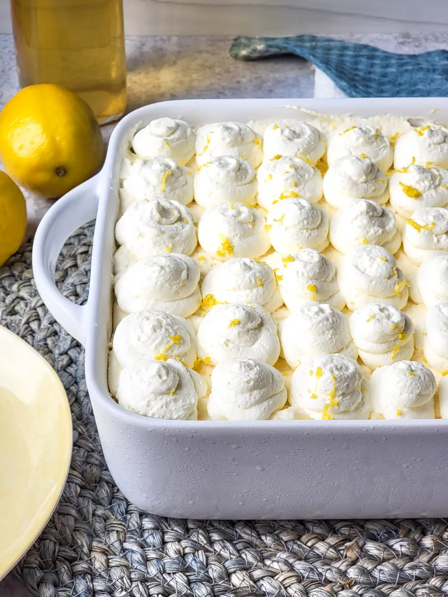 Limoncello tiramisu in a white dish with ingredients surrounding it.