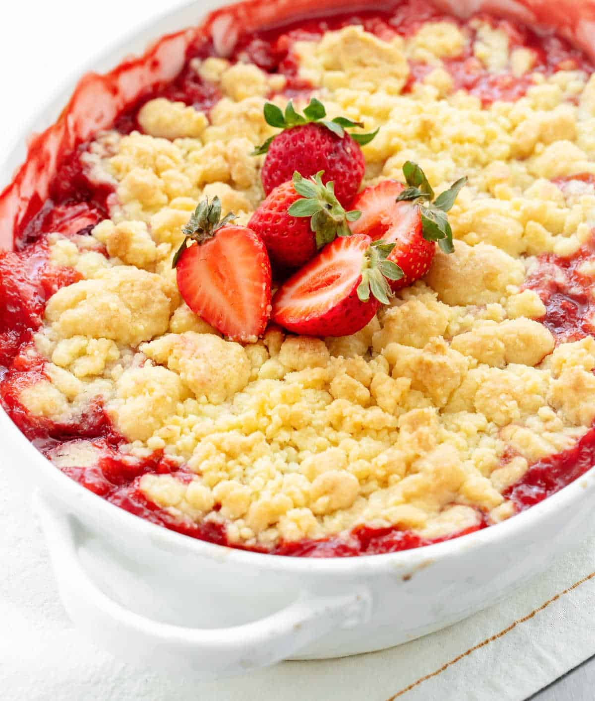 Strawberry dump cake in a baking dish with fresh strawberries on top.