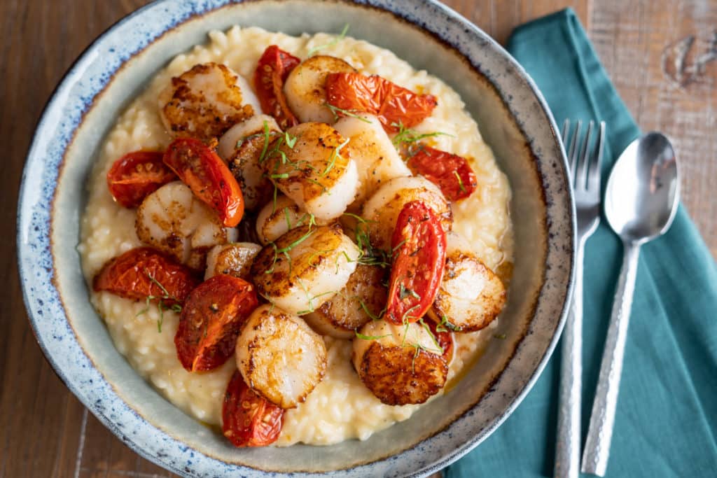 Truffle risotto with scallops with roasted tomatoes om a bowl.