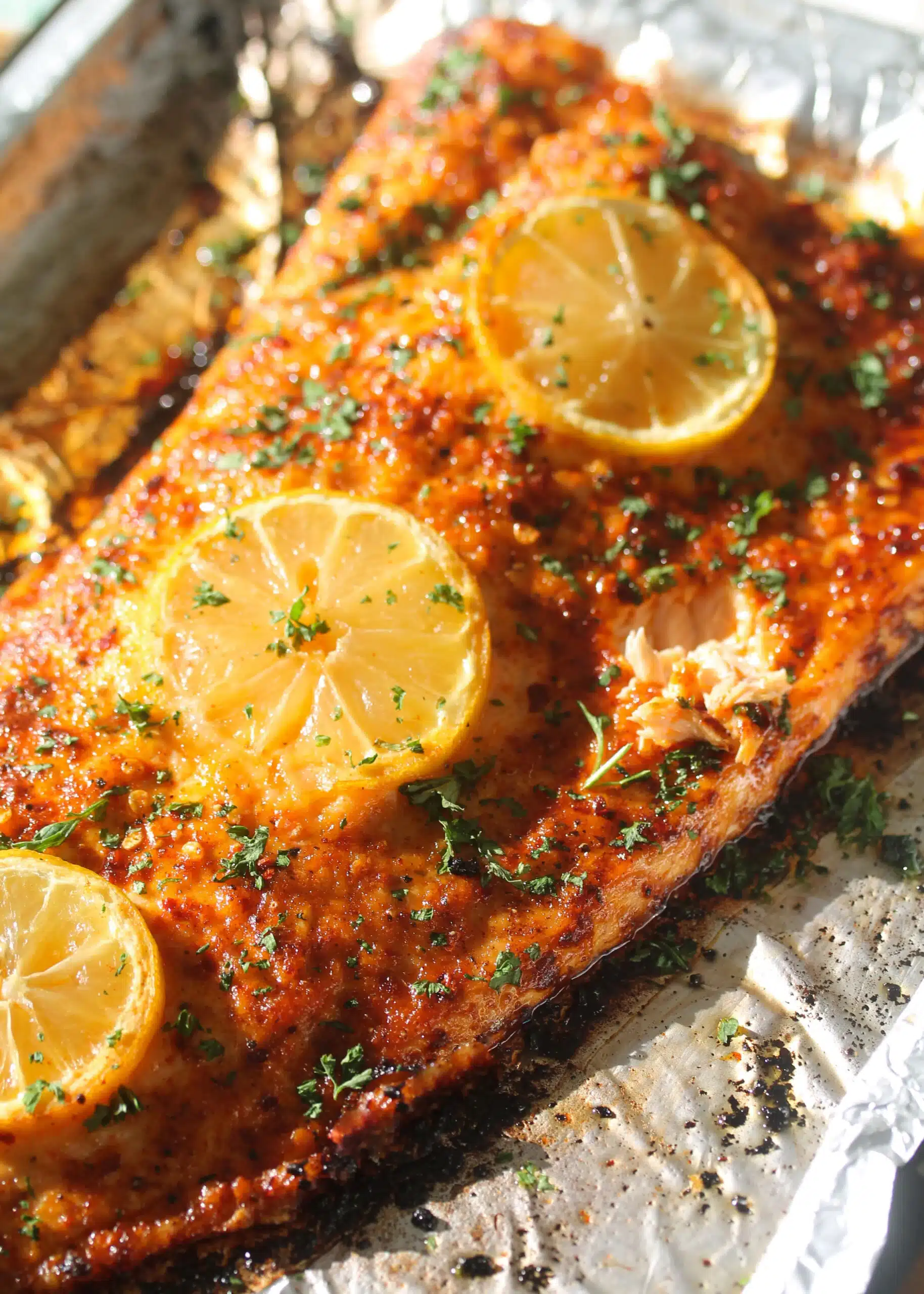 Oven baked salmon with lemon and pepper on a aluminum lined pan.