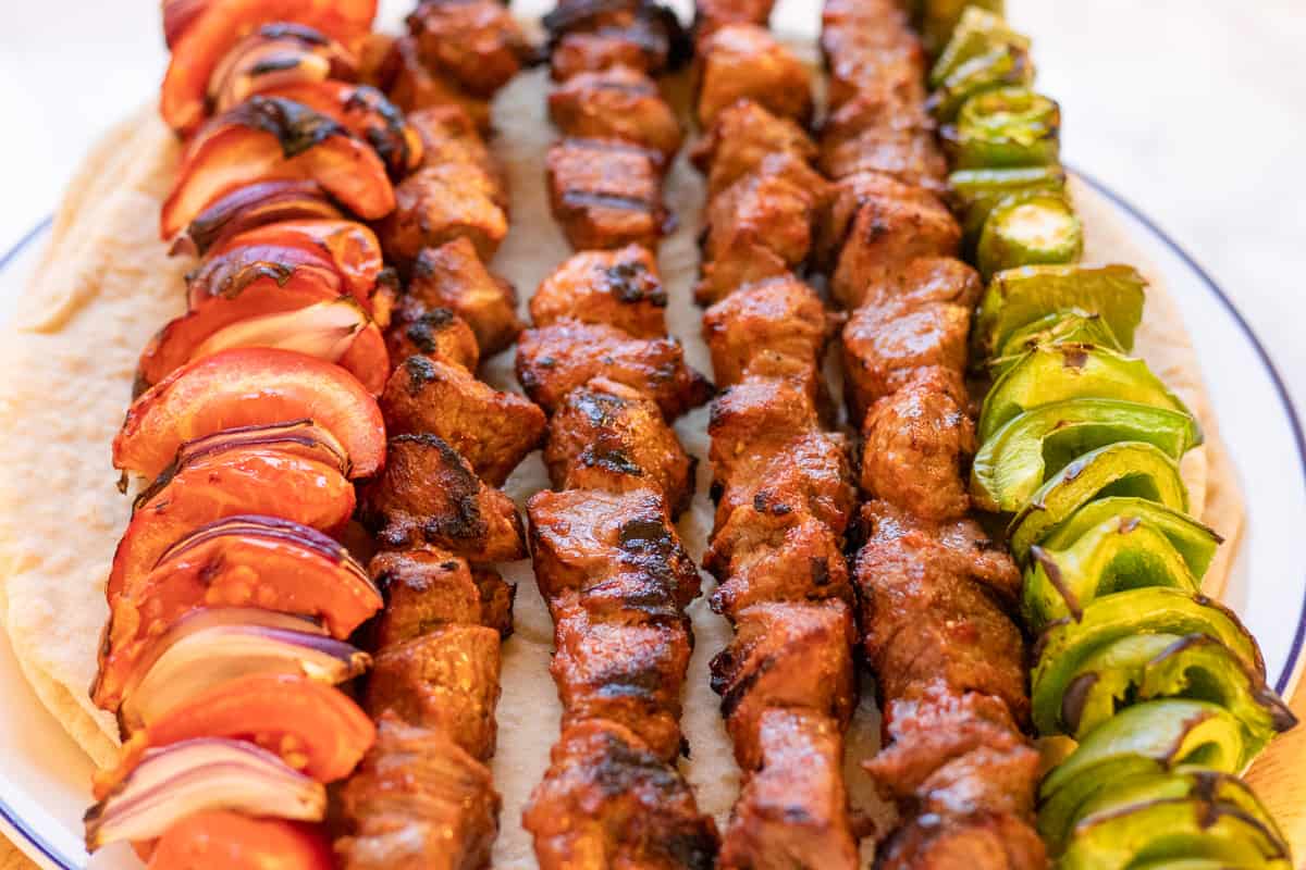 Lamb shish kababs with tortillas on a plate.