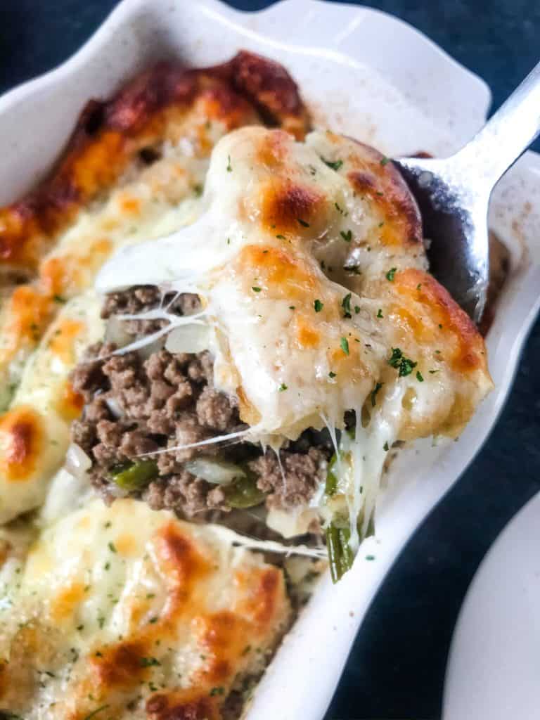 Spoon scooping out a serving of Philly cheesesteak tater tot casserole.