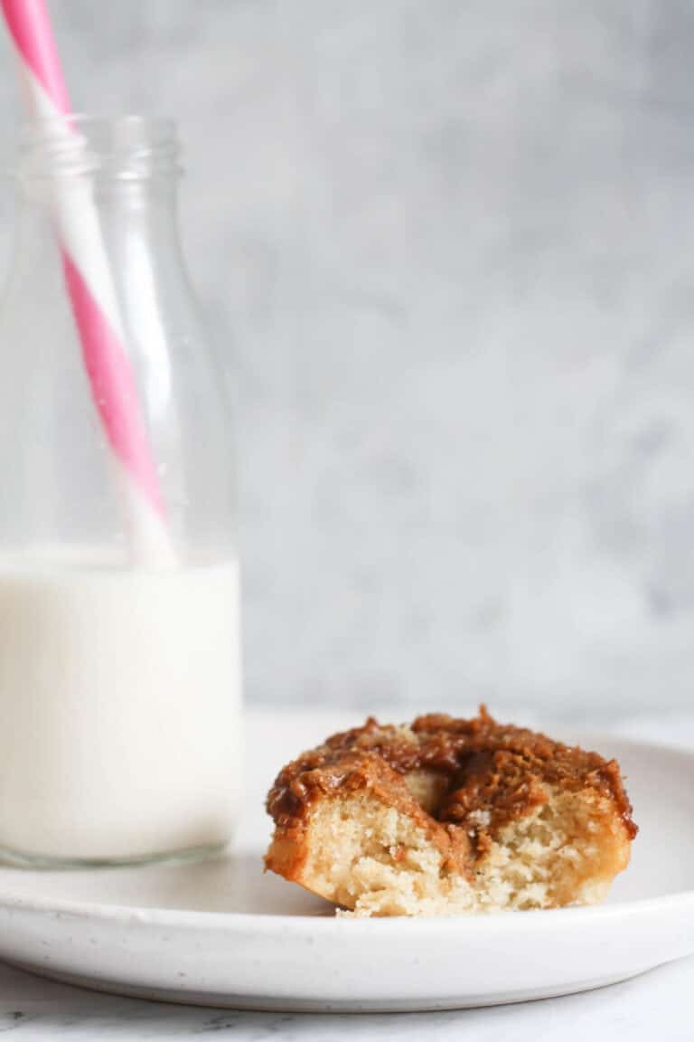 Baked Biscoff donut recipe on a white plate with glass of milk.