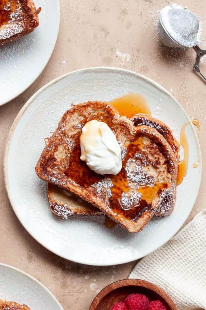 Anabolic French toast with dollop of Greek yogurt and syrup on a white plate.