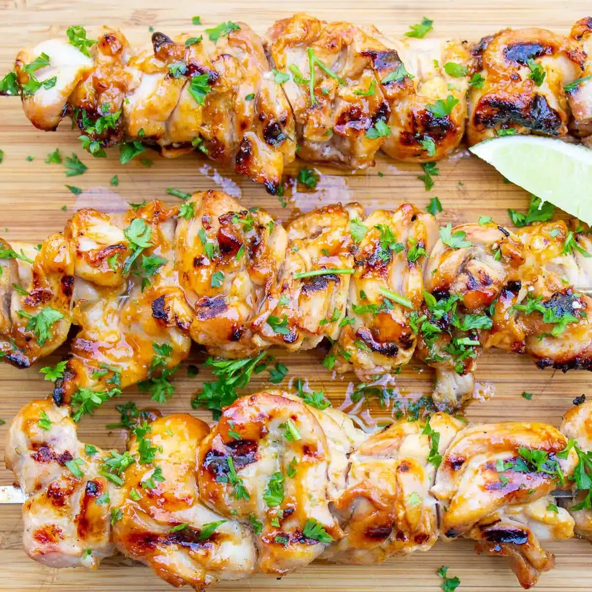 Spicy honey lime chicken skewers on a cutting board.