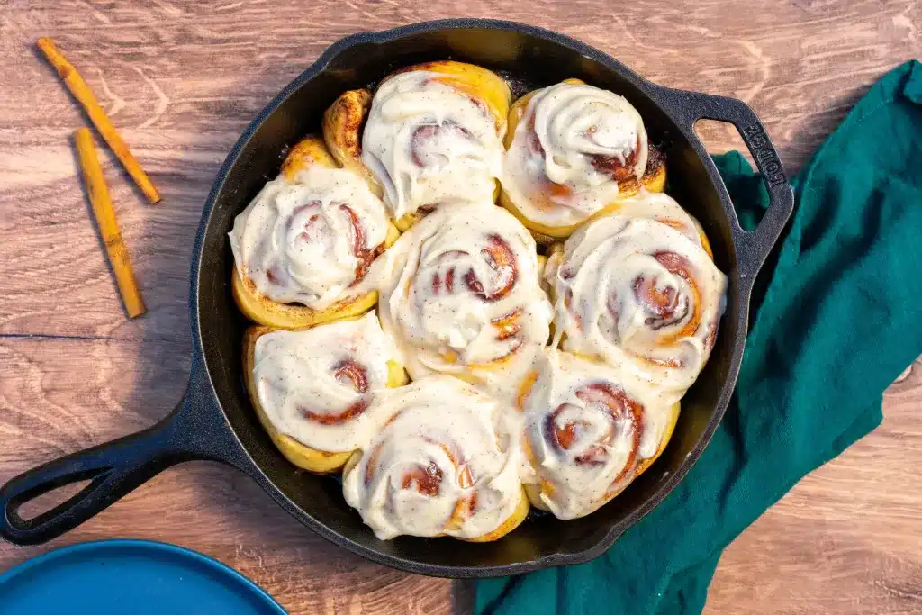 Sourdough cinnamon rolls with brown butter cream cheese in cast iron pan.