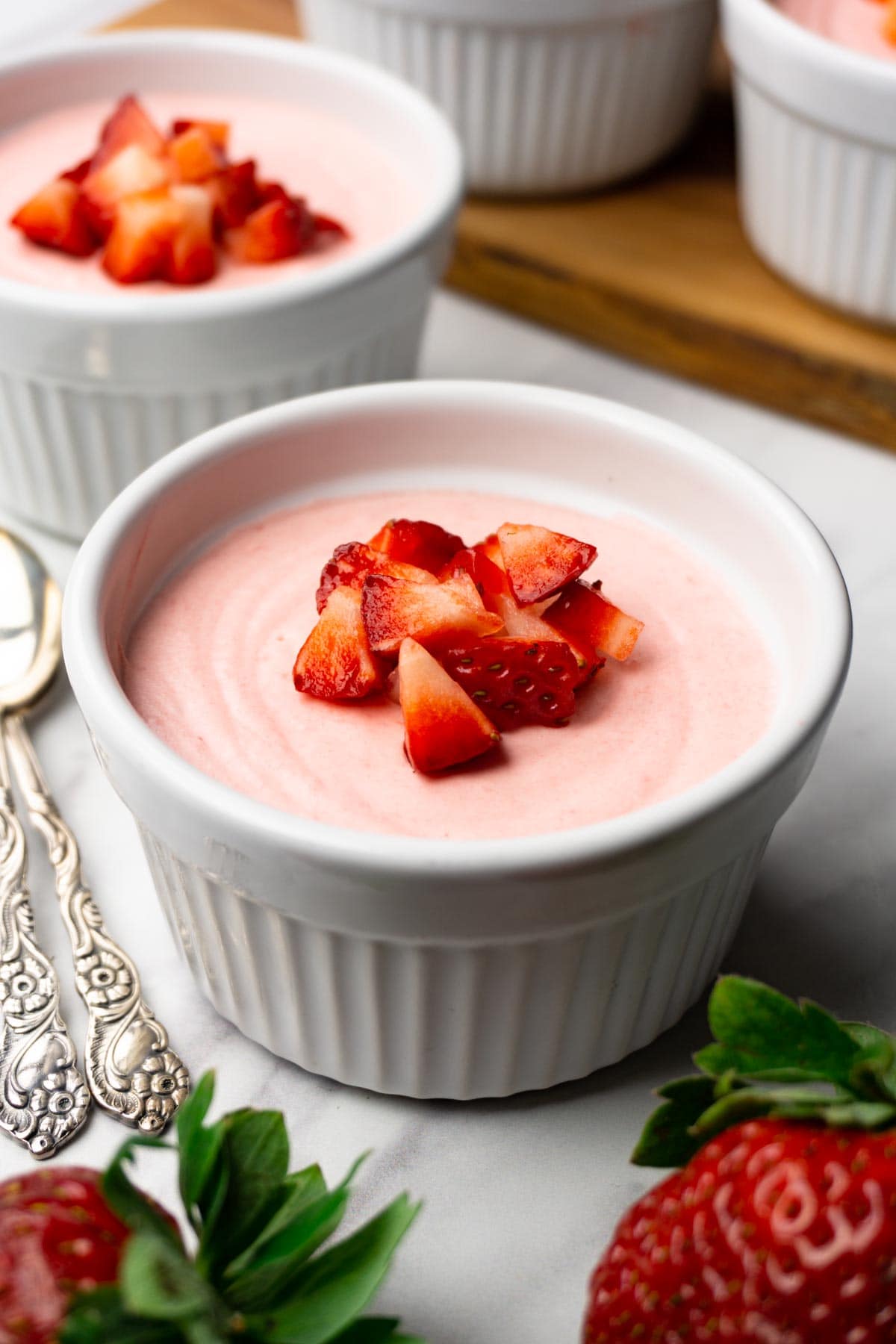 Strawberry mousse in white ramekins with diced strawberries on top.