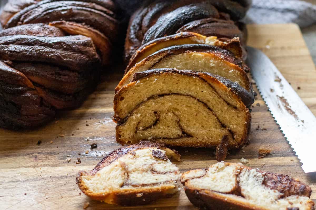 Sliced chocolate babka bread on a cutting board with bread knife in the background.