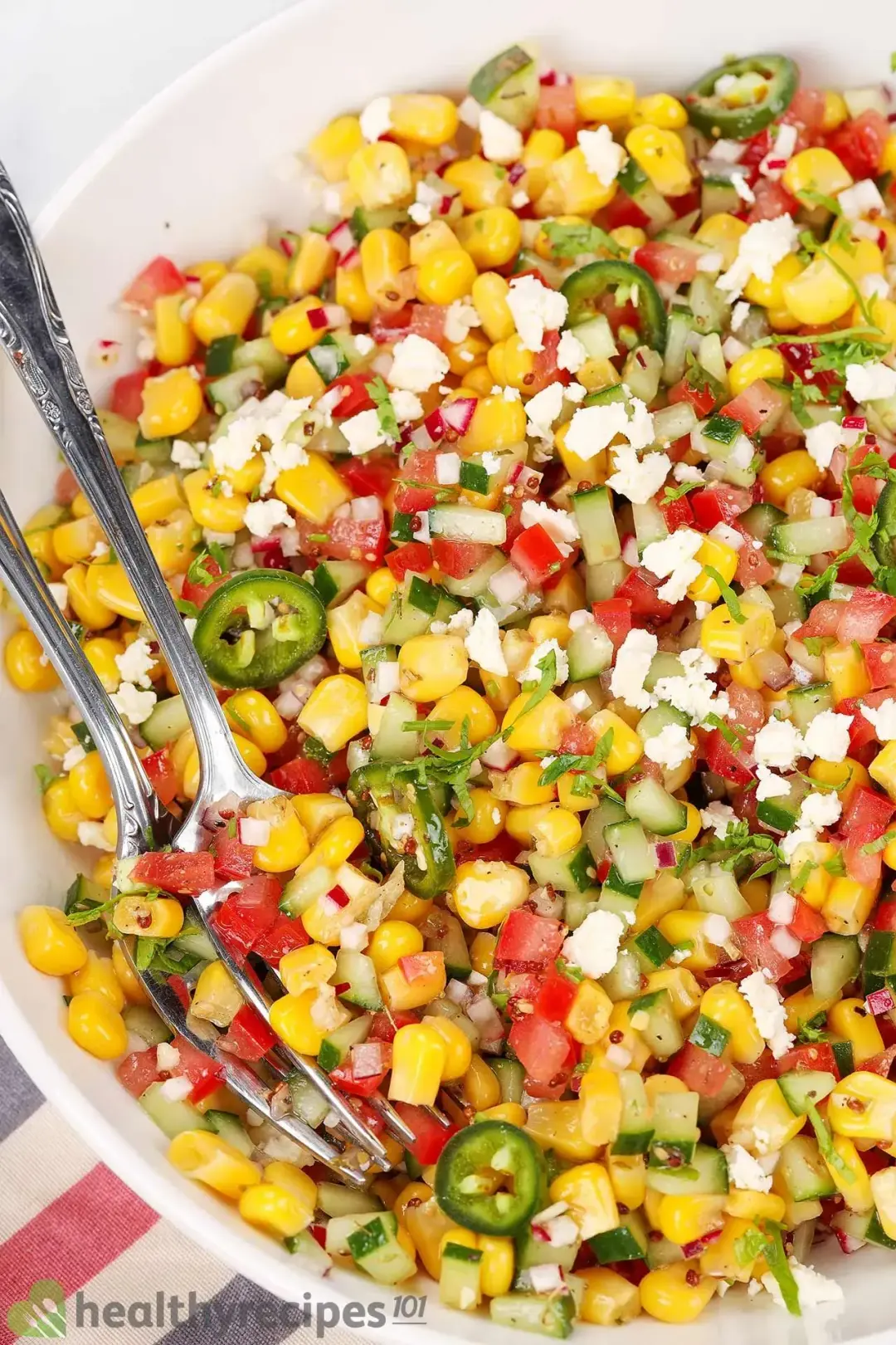 Corn salad with cucumber, radish, onion, and jalapeno in a bowl.