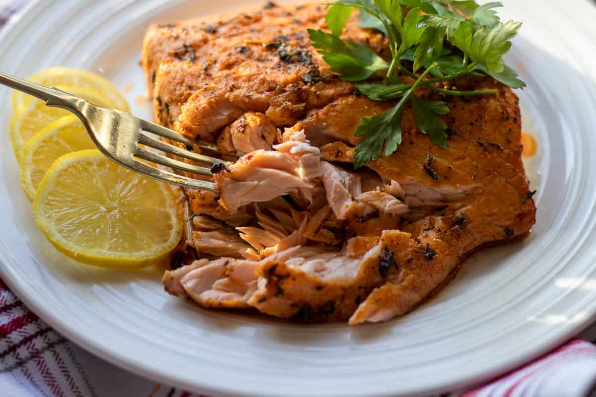 Mediterranean baked salmon on a white plate.