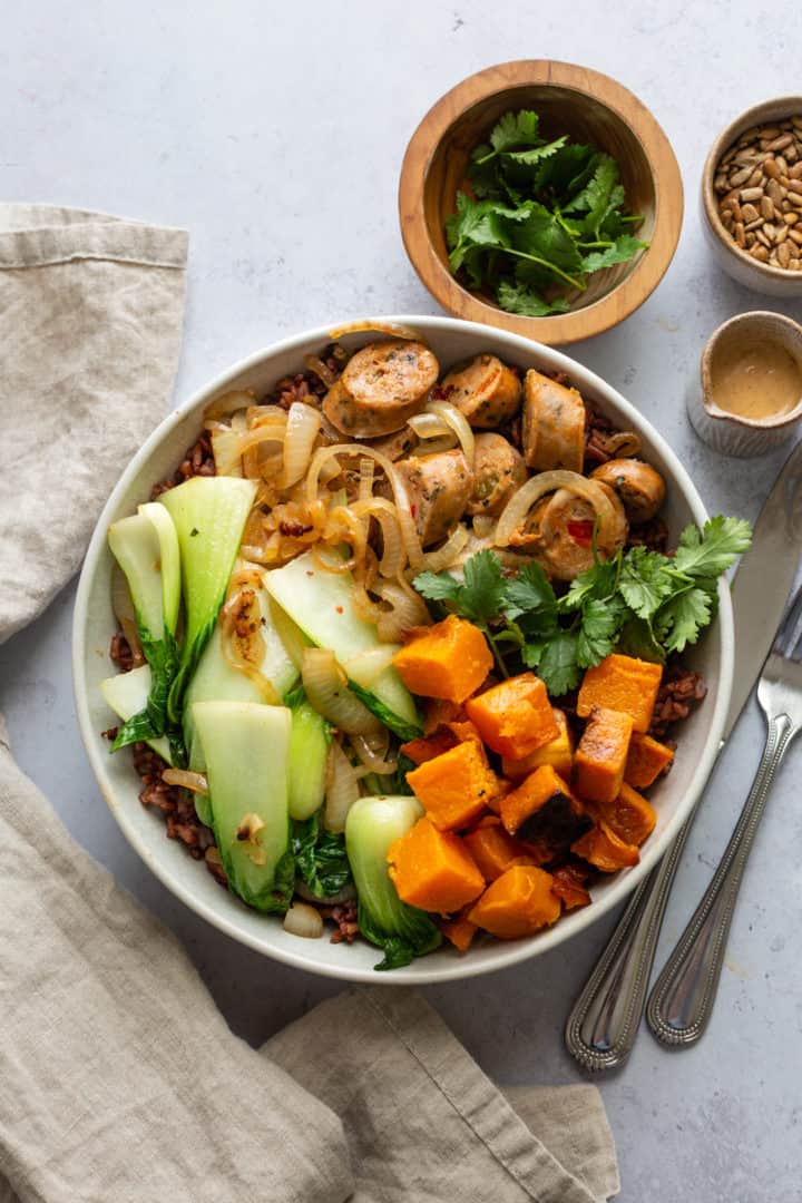 Bowl with chicken sausage, squash, bok choy, sauteed onions, and grains.