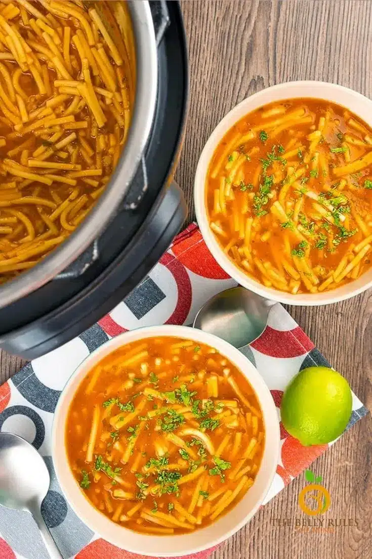 Mexican noodle soup in bowls with Instant Pot, spoons, and lime in the background.