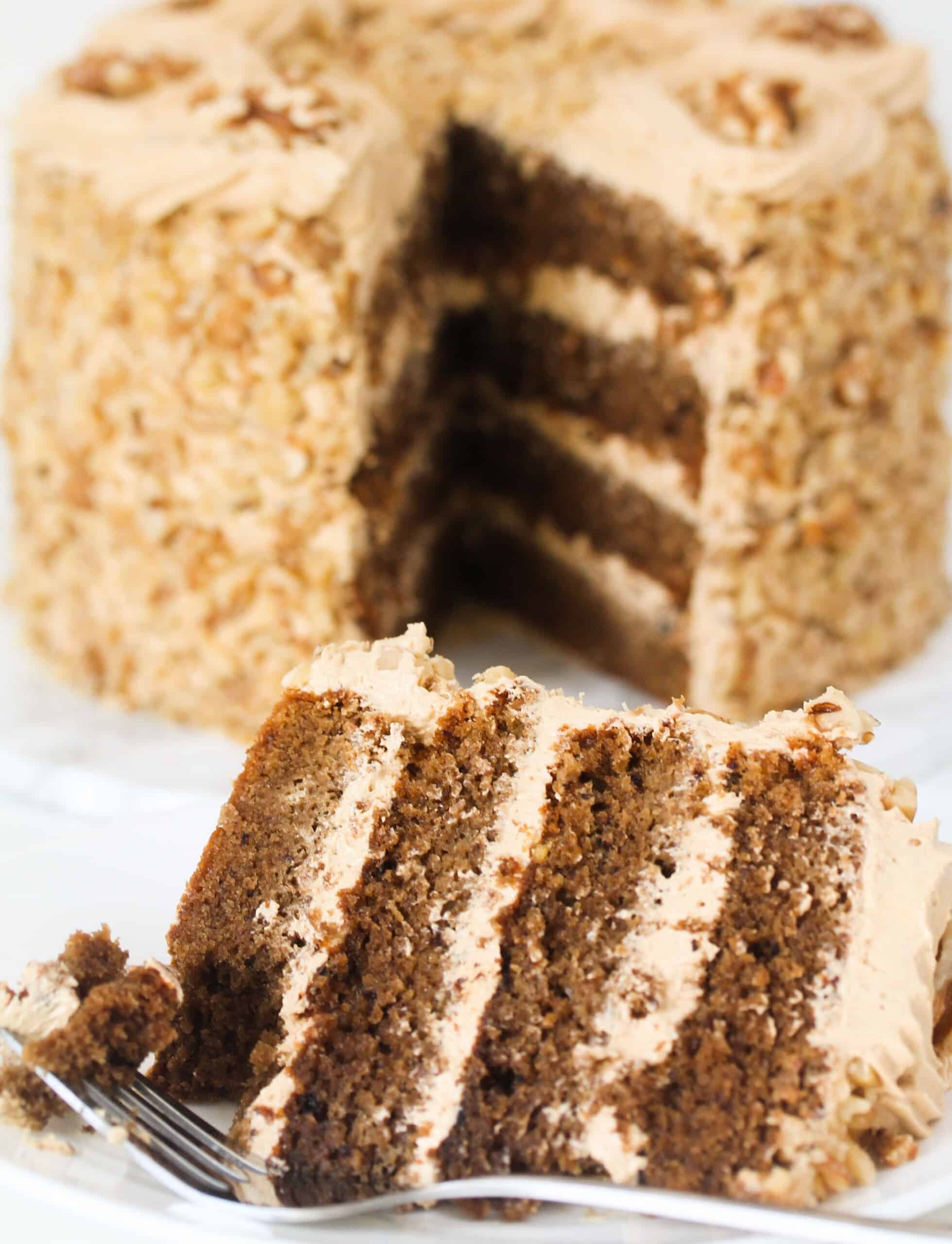 Slice of coconut and walnut cake on a saucer with fork.