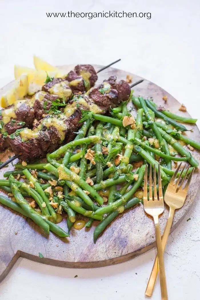 Steak kabobs with dijon mustard green beans on a serving tray.