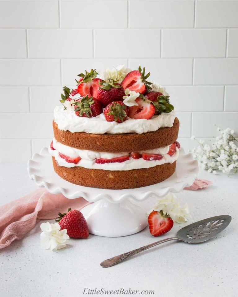 Strawberry shortcake cake with fresh strawberries on top on cake stand.