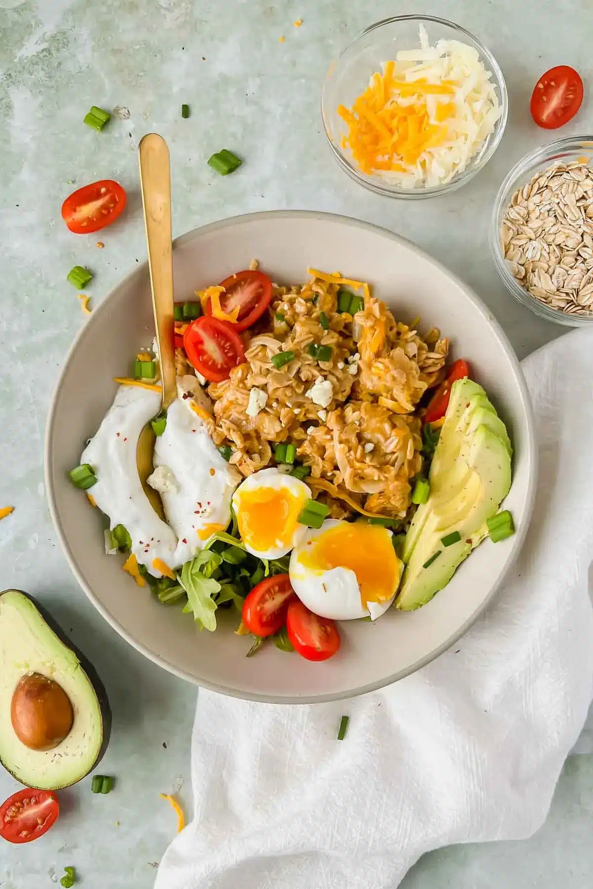 Cheesy oatmeal with tomatoes, soft-boiled eggs, avocado, and arugula.