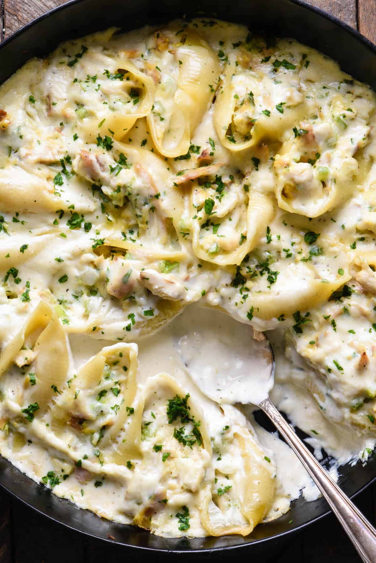 Turkey alfredo stuffed shells in a cast iron pan.