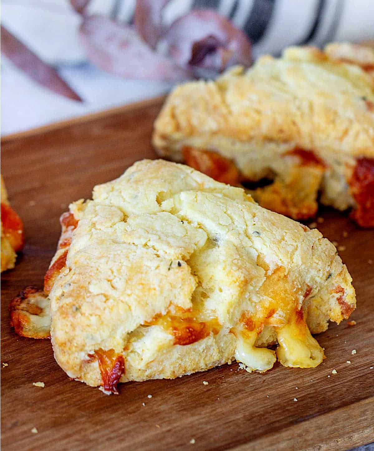 Double cheese scones on a wooden cutting board.