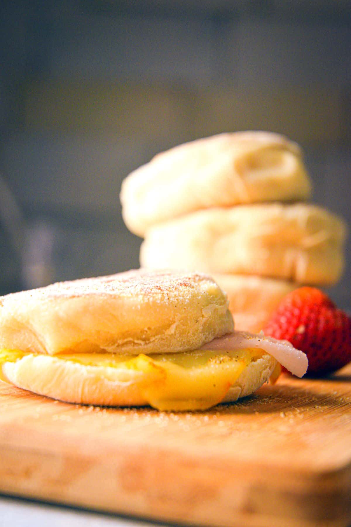 English muffin with ham and cheese sandwich with a stack in the background.