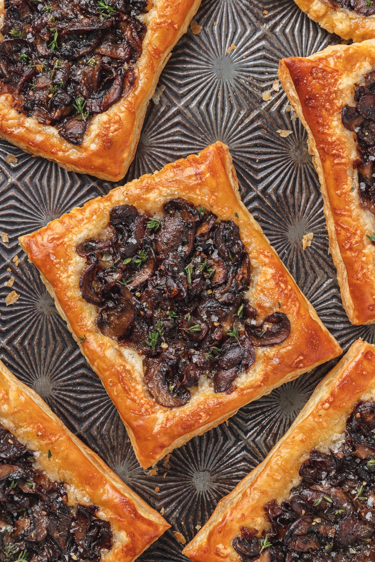 Caramelized mushroom with gruyere puff pastry tart on a silver tray.