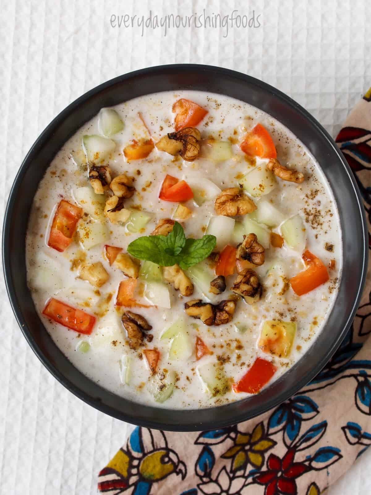 Savory oatmeal with steel cut oats with walnuts, tomatoes, and onions in a bowl.