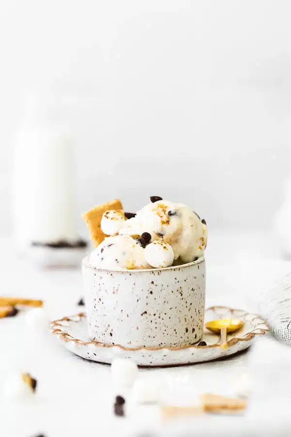 Serving of s'mores ice cream in a decorative mug on a saucer with a spoon.